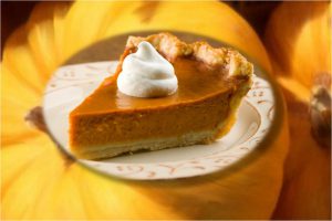 slice of pumpkin pie on plate in front of whole pumpkins