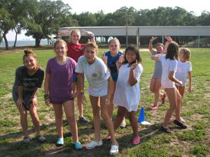 A group of girls celebrating a win after an outdoor game at 4-H camp.