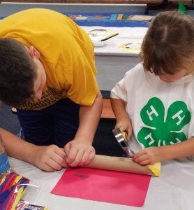 A volunteer is helping a child with a hammering craft project.