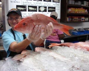 photo of market clerk holding a red snapper