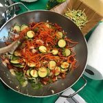Carrots, zucchini, and green pepper stir fry in a wok.