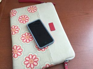 picture of a cell phone on a flowered material case on a woodgrain desk