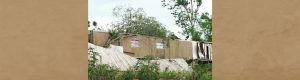 Tree fallen on brown trailer, wooden fence knocked over - banner