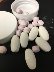 small round pink pills and oblong white pills with round pill box