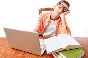 teen boy sleeping in front of laptop