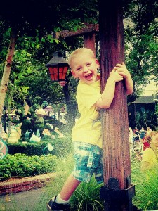 Child hugging a wooded ploe in a garden