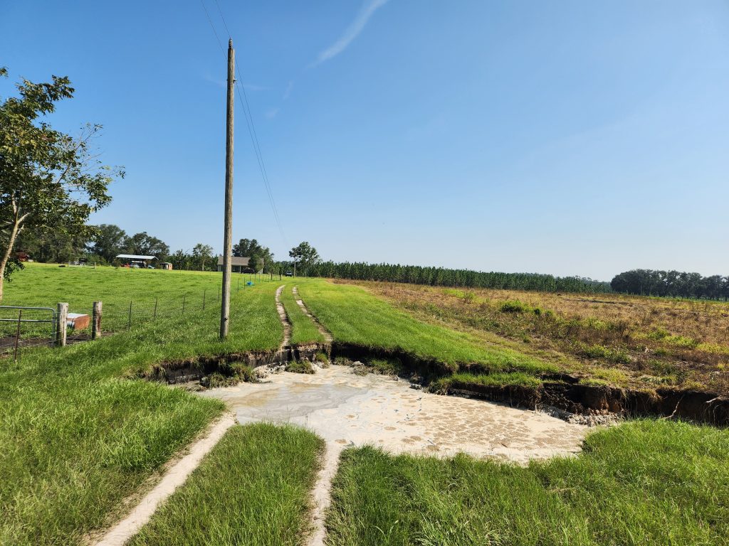 A sinkhole is shown. It opened on the dge of a harvested crop field, and cut across a small dirt road.